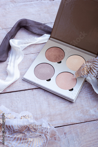 Side view of luxury bronzer and highlighter palette on a shebby wooden background. Unpacking. Beautiful silk ribbons in white and purple colors. Copy space. photo