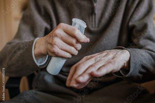 Old man disinfects hands with antibacterial liquid