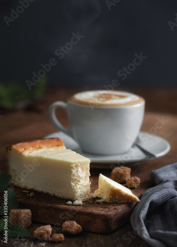 cutaway cheesecake, with mint, pieces of cane sugar, cappuccino on a wooden board