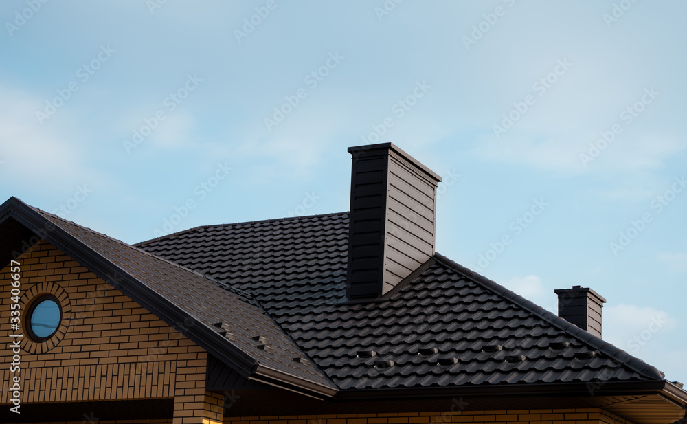 Brown metal tile roof. Roof metal sheets. Modern types of roofing materials. Roof of the house, metal roof tile against the blue sky. Building. Brown metal tile roof. Roof metal sheets. Modern types of roofing materials. Roof of the house, metal roof tile against the blue sky. Building.