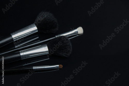make up brushes lying on black glass table. photo with selectiv focus, low key photo