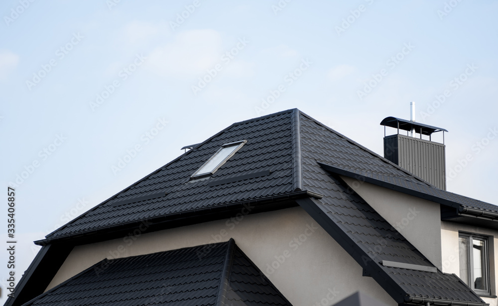 Foto Stock Black metal tile roof. Roof metal sheets. Modern types of  roofing materials. Roof of the house, metal roof tile against the blue sky.  Building. | Adobe Stock