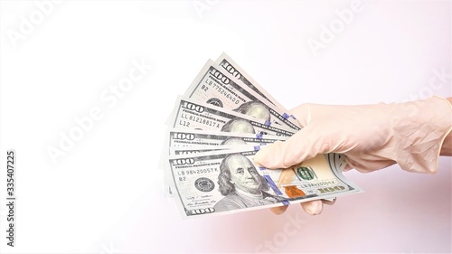 Hands in medical gloves holding a bundle of dollars a white background. The concept of infection on money, dirty money epidemic coronavirus,COVID-19, paid medicine, treatment fees, bribes, illegal sur