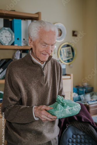 Cheerful senior holding home-delivered meal, quarantine during pandemic Covid-19