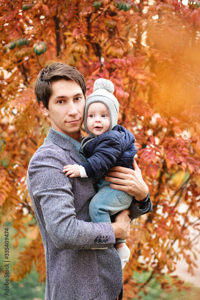a young son is sitting in the arms of a young father a young son is sitting in the arms of a young father