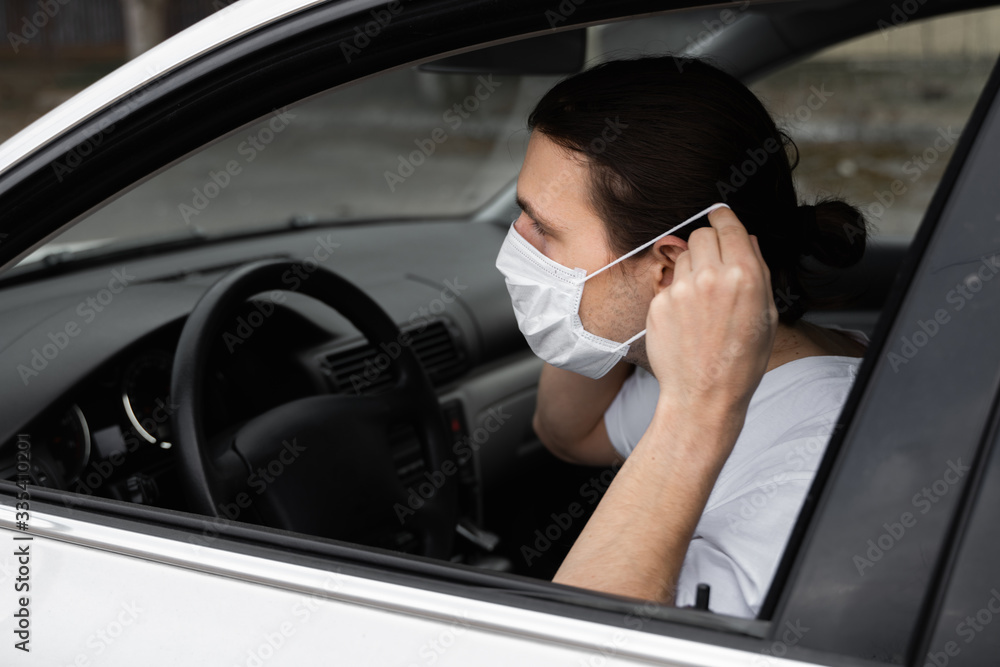 Man in protective medical mask for protect himself from bacteria and virus is planning to drive a car. Protective mask while epidemic, quarantine, world pandemic, covid 19, coronavirus, infection.
