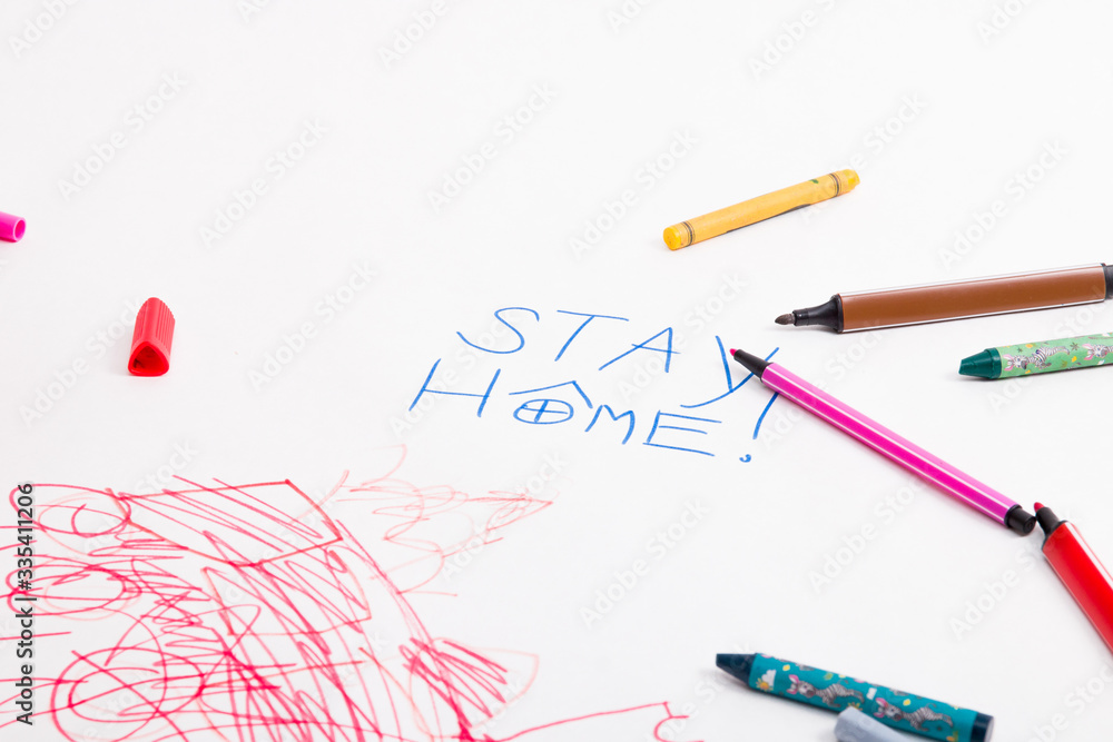 inscription on white paper stay home, felt-tip pens and wax crayons lie on drawing paper, child's drawing, activities with the child during quarantine, development of children inscription on white paper stay home, felt-tip pens and wax crayons lie on drawing paper, child's drawing, activities with the child during quarantine, development of children