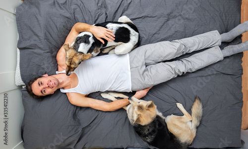 Man and dogs lying on bed with gray sheet