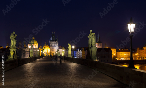 Night colorful Prague Old Town with Bridge Tower and St. Francis of Assisi Cathedral from Charles Bridge with its baroque Statues without People at the time of Coronavirus, Czech republic