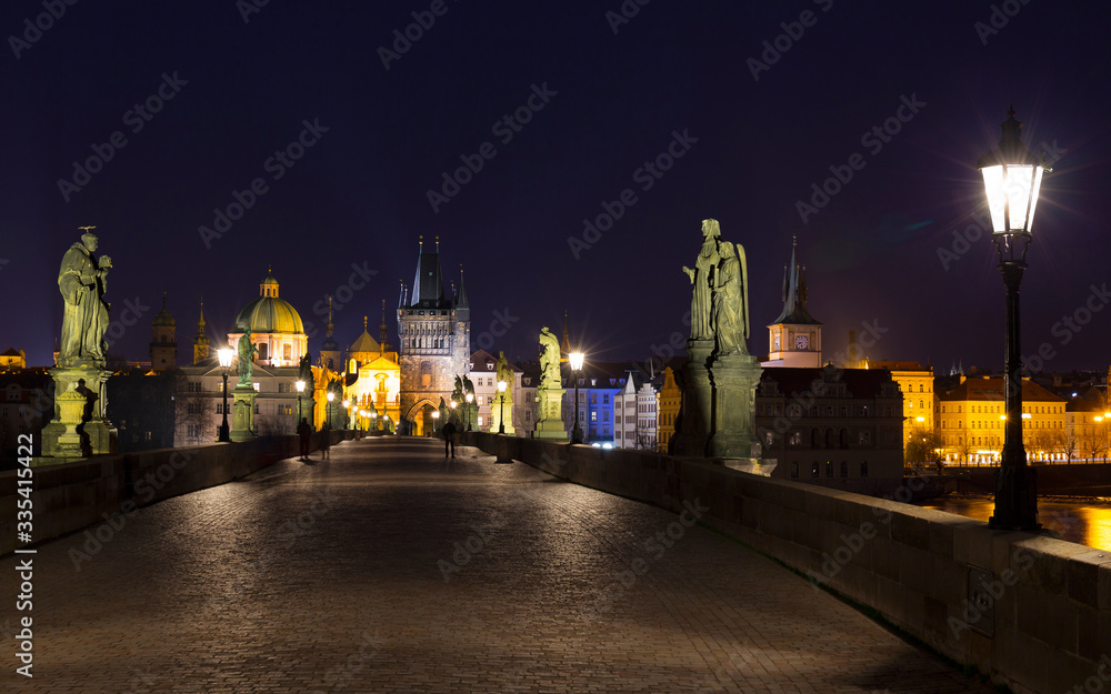 Night colorful Prague Old Town with Bridge Tower and St. Francis of Assisi Cathedral from Charles Bridge with its baroque Statues without People at the time of Coronavirus, Czech republic