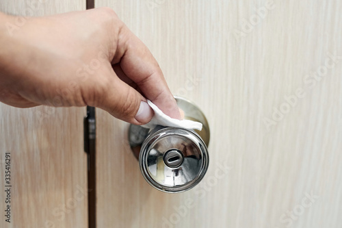 A person treats a round door handle with an alcohol-based disinfectant to prevent viral infection. Coronovirus COVID-19. The fight against germs and bacteria