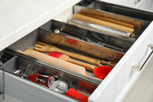 Different utensils in open desk drawer indoors, closeup