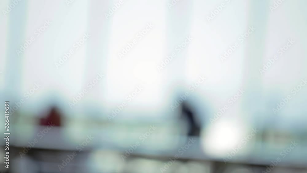 A blurred defocused and canted view of pedestrians walking by in a modern office building. A blurred defocused and canted view of pedestrians walking by in a modern office building.