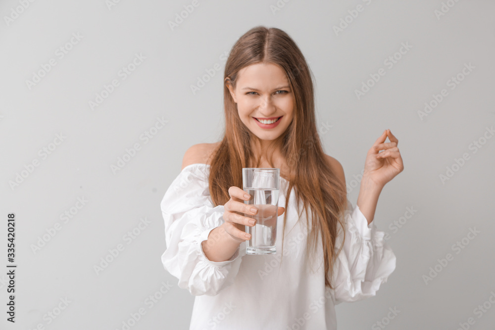 Beautiful young woman with glass of water on light background Beautiful young woman with glass of water on light background