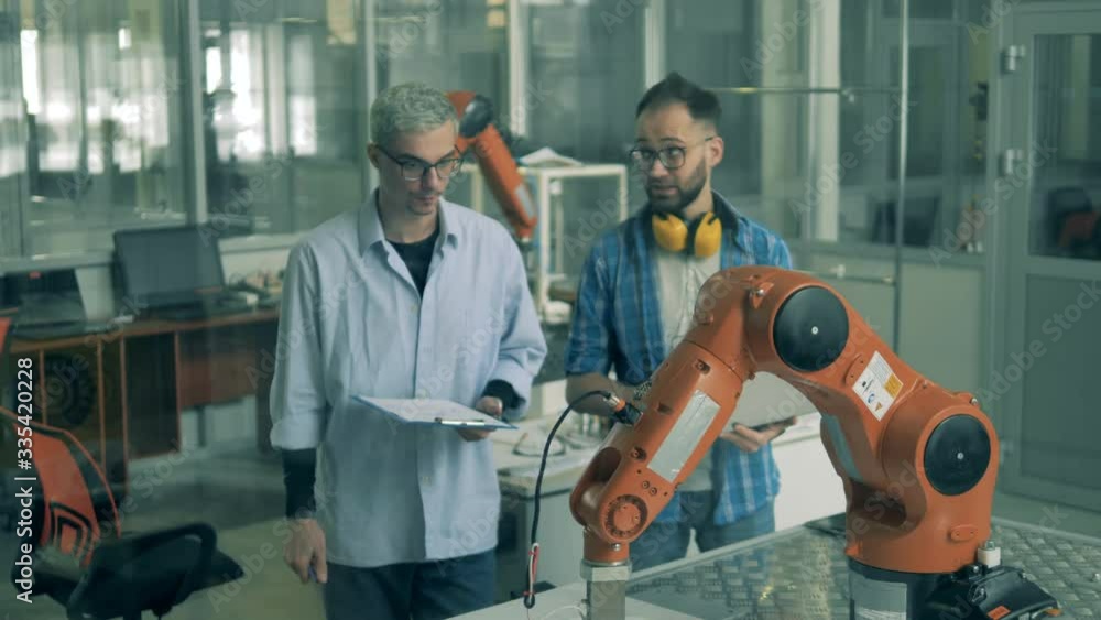 Laboratory assistants are watching a robotic mechanism Laboratory assistants are watching a robotic mechanism