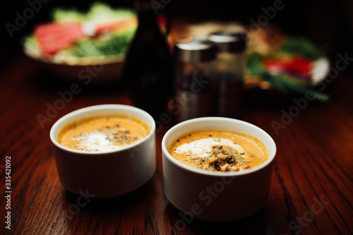 Vegetarian autumn pumpkin puree and carrot cream soup with seeds,crumbled croutons and dried spices.Butternut squash soup recipe,vegetarian keto healthy food concept.Plant based dinner