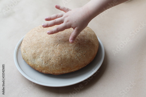 A child's hand reaches for the freshly baked bread. The concept of cooking delicious and healthy food at home.