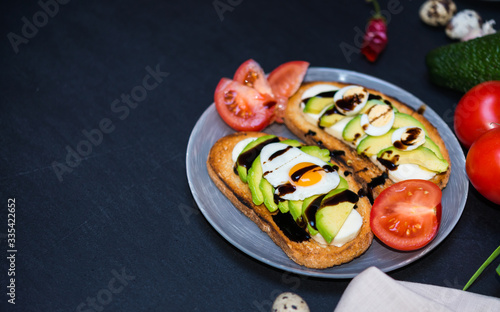 Healthy food. Avocado Sandwich and Vegetables. Toast with White Soft Cheese, Sliced Avocado, Quail Fried and Boiled Eggs Poured Balsamic Sauce for Healthy Breakfast or Snack