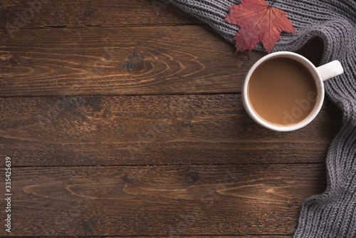 Flatlay composition with knitted scarf  cup of coffe on wooden desk table. Hygge style  cozy autumn or winter holiday concept. Flat lay  top view  overhead.