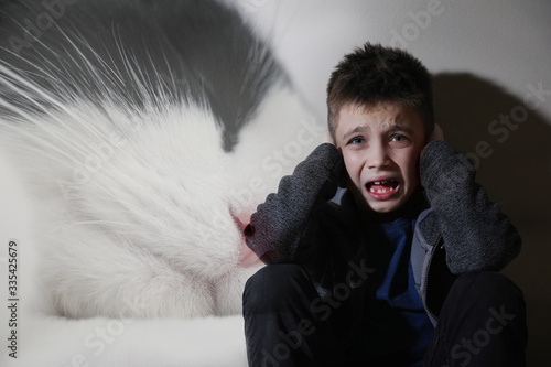 Little boy suffering from ailurophobia. Irrational fear of cats photo