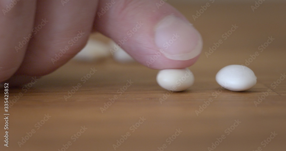 Finger adds a second bean to one already on wooden table top, metaphor for bean counting accountants. Macro with shallow focus Finger adds a second bean to one already on wooden table top, metaphor for bean counting accountants. Macro with shallow focus