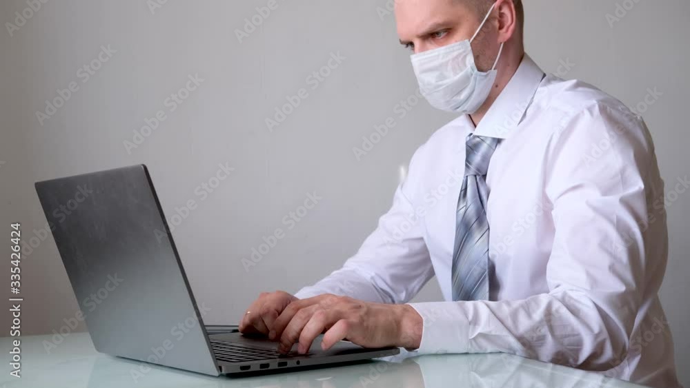 4k Man in medical mask and office clothes white shirt and tie talks business remotely from home on laptop. The call to stay home safe. Distance work. Quarantine. 4k Man in medical mask and office clothes white shirt and tie talks business remotely from home on laptop. The call to stay home safe. Distance work. Quarantine.
