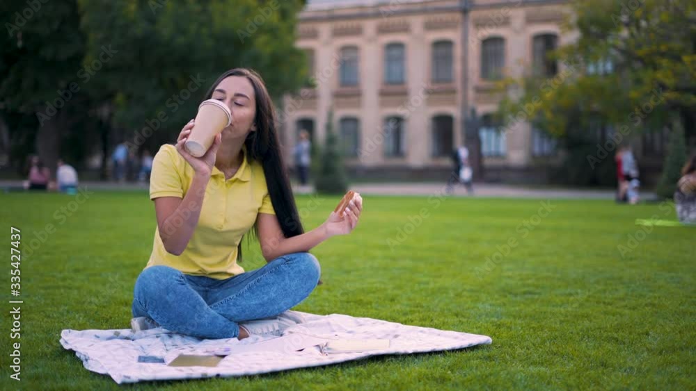 Coffee to go. long-haired latino girl sitting in the park and having lunch. 4K Coffee to go. long-haired latino girl sitting in the park and having lunch. 4K