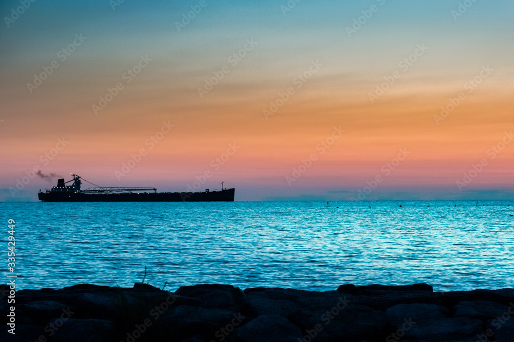 Cargo ship coming into harbor, on at sunset, colorful sky Cargo ship coming into harbor, on at sunset, colorful sky