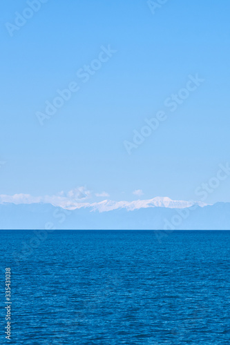 Tropical blue sea and blue sky with mountains on a horizon as a natural background. Copy space.