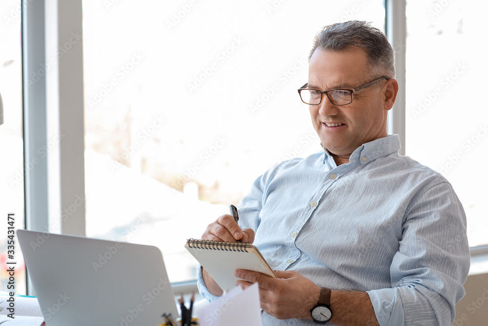 Mature man using laptop at home - obrazy, fototapety, plakaty 