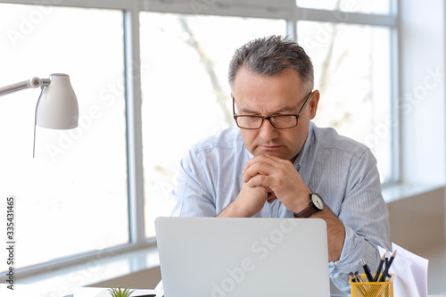 Mature man using laptop at ...