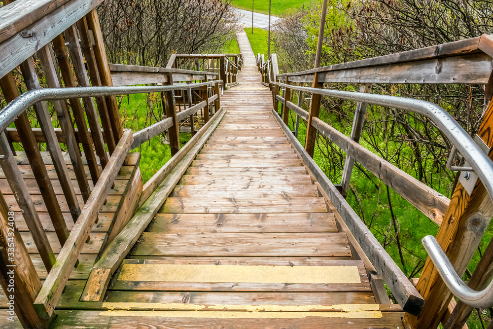 Obraz premium Looking down a long wooden staircase headed down hill to a park