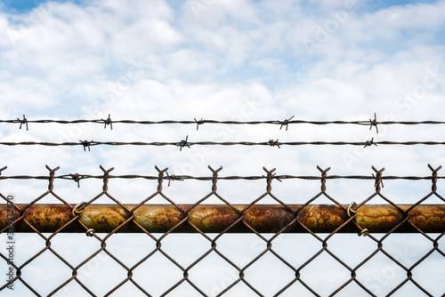 Vibrant colors, rusty chain link fence topped with barbed wire. Selective focus - background - graphic
