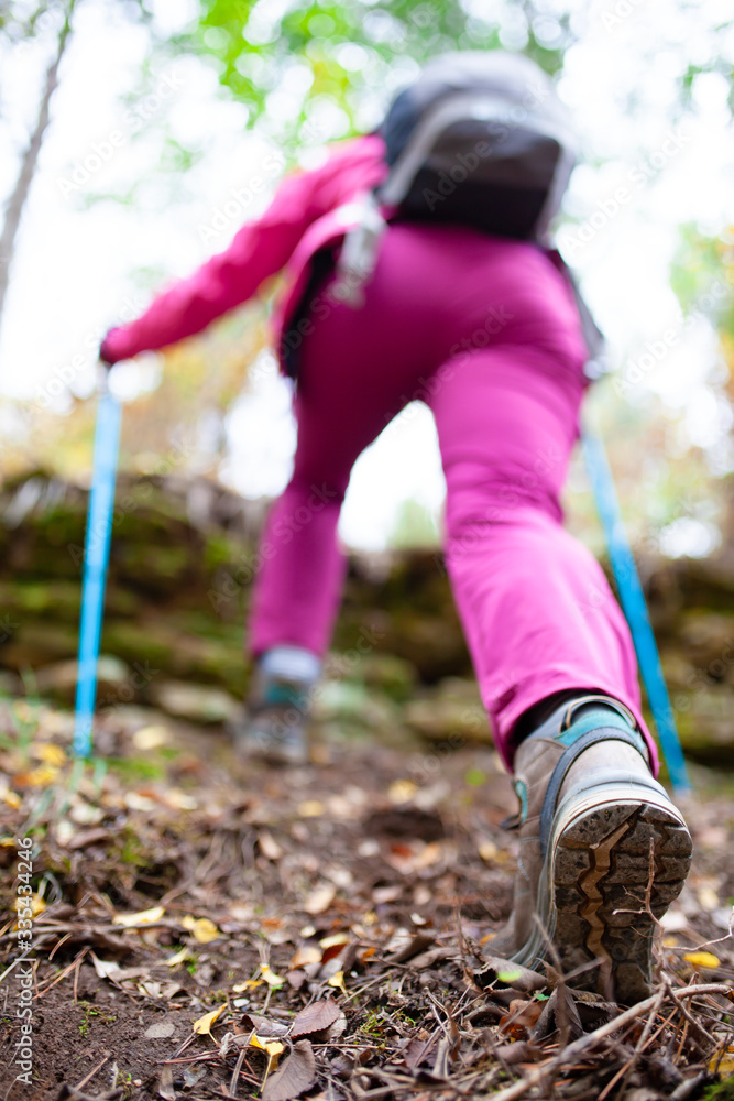 Hiking girl in a mountain. Low angle view of generic sports shoe and legs in a forest. Healthy fitness lifestyle outdoors. Hiking girl in a mountain. Low angle view of generic sports shoe and legs in a forest. Healthy fitness lifestyle outdoors.