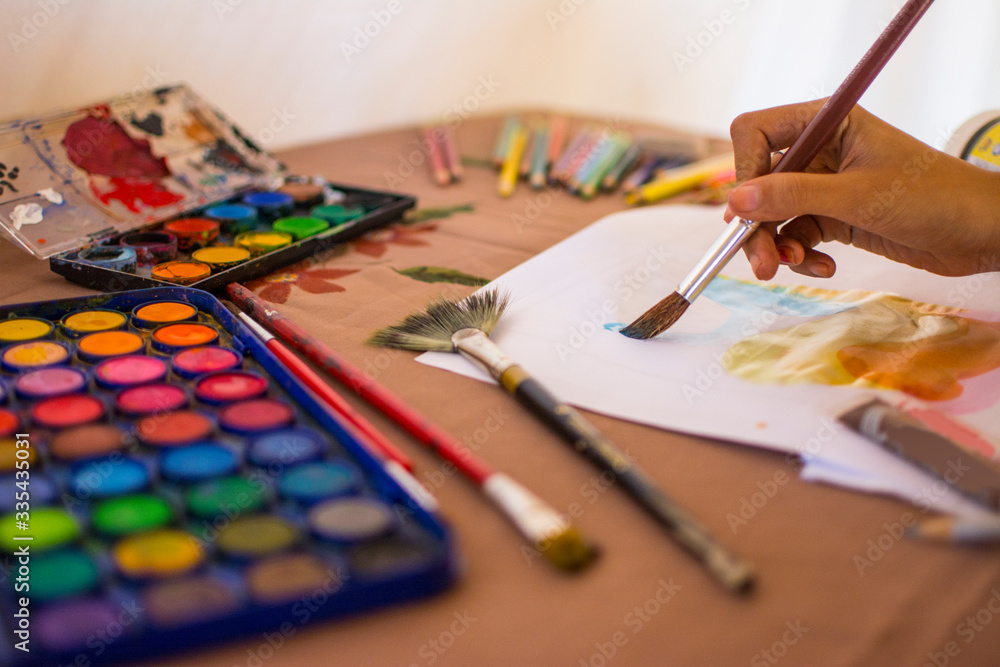 Artist woman painting with watercolors with her brush and colored pencils Artist woman painting with watercolors with her brush and colored pencils