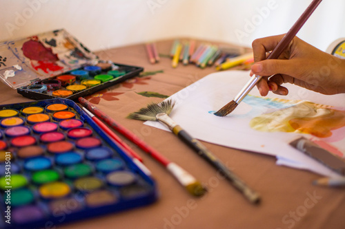 Artist woman painting with watercolors with her brush and colored pencils
