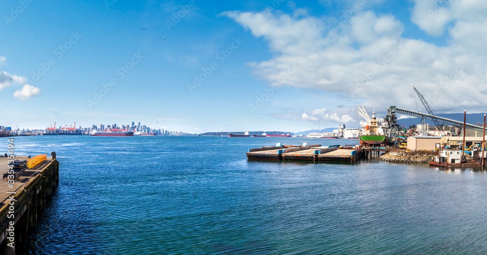 Panoramic view downtown Vancouver. From North Vancouver, by Second Narrows Bridge / Iron Workers Bridge. Port industry foreground. Background: City skyline, cargo ships, port cranes and Stanley Park.