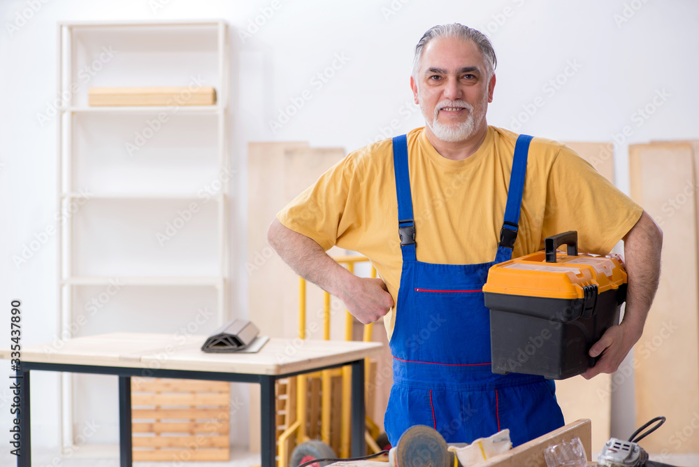 Old male carpenter working in workshop Old male carpenter working in workshop