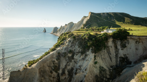 White house build on the cliff with cape and ocean in background. Shot made during cloudless sunny day on Cape Kidnappers Trail, New Zealand