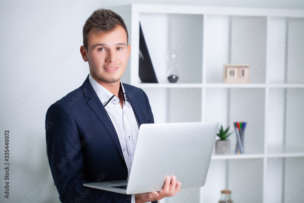 Handsome young worker working in a company office with documents and a laptop Handsome young worker working in a company office with documents and a laptop