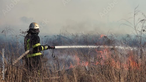 Firefighter puts out a forest fire near the city. Burning grass with smoke among the bushes and trees. Air pollution and ecology. Fires caused by drought and climate change. Arson Grass. Firemen 