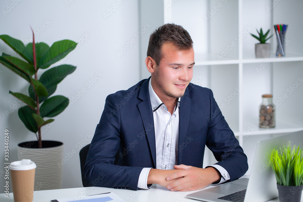 Handsome young worker working in a company office with documents and a laptop Handsome young worker working in a company office with documents and a laptop