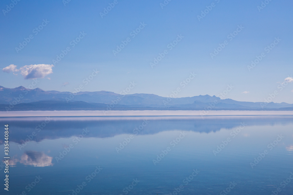 panorama of blue calm lake and reflection of mountains, clouds in the water