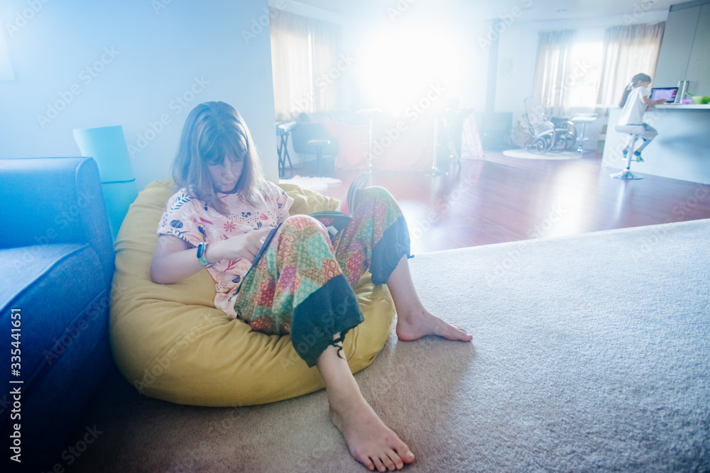 Naklejka premium young teen girl reading at home, home schooling, remote education at quarantine