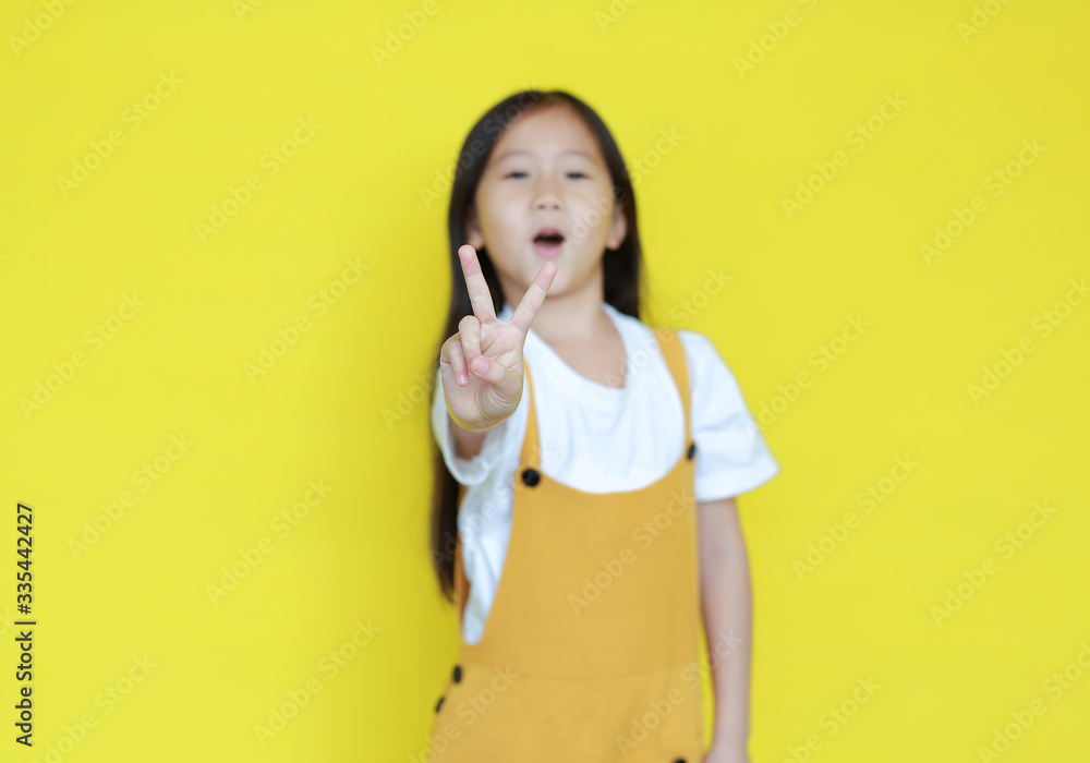 Portrait of little child girl showing two finger gesture as sign as fighting isolated over yellow background. Portrait of little child girl showing two finger gesture as sign as fighting isolated over yellow background.