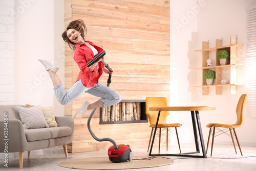 Young woman having fun while vacuuming at home