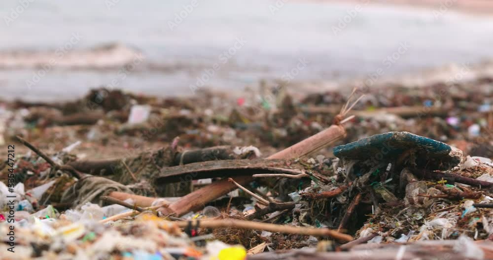 The worlds most polluted beach in Bali. Plastic bags bottles and paper trash on the sandy dirty beach. Sea waves full of litter hitting the beach. Huge dump in tropical paradise. Marine pollution.