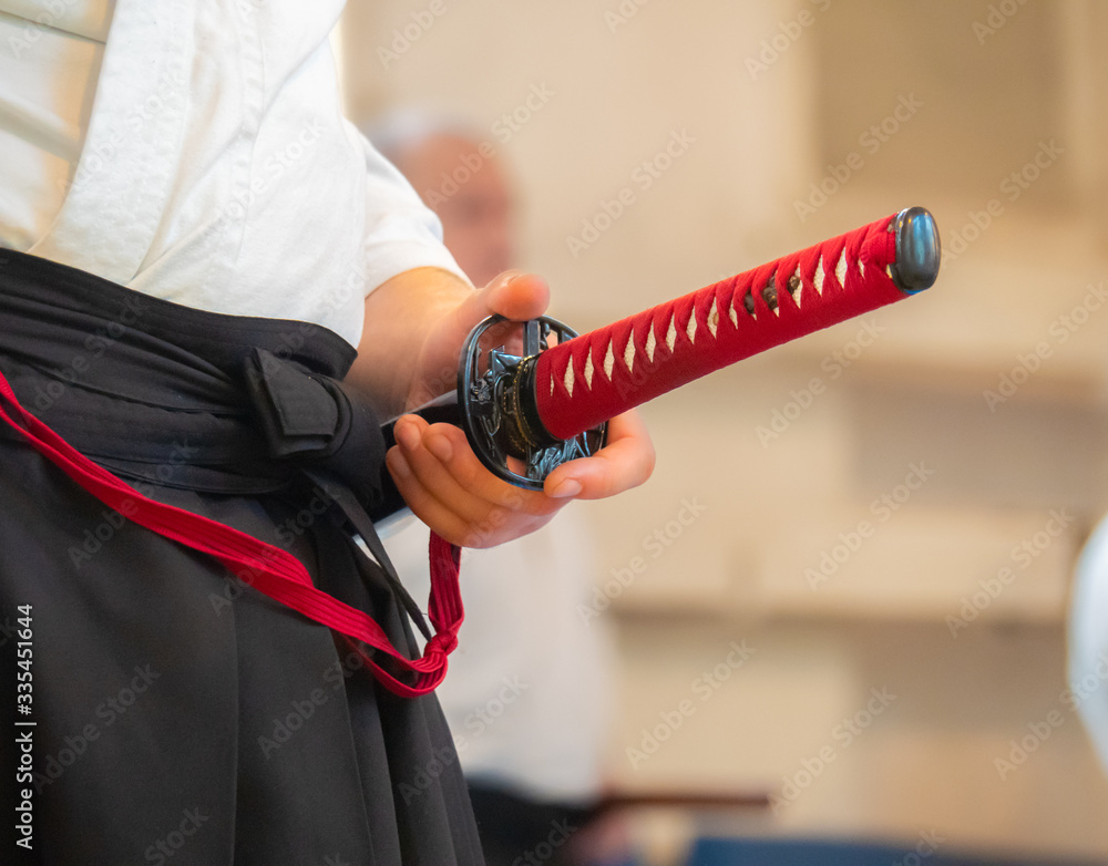 Man dressed in keikogi and hakama stay with japanese sword close up