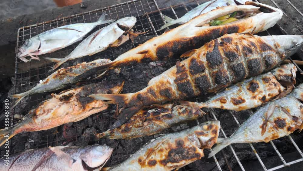 Delicious fresh grilled fish on a grilling tray being cook by charcoal. Delicious fresh grilled fish on a grilling tray being cook by charcoal.
