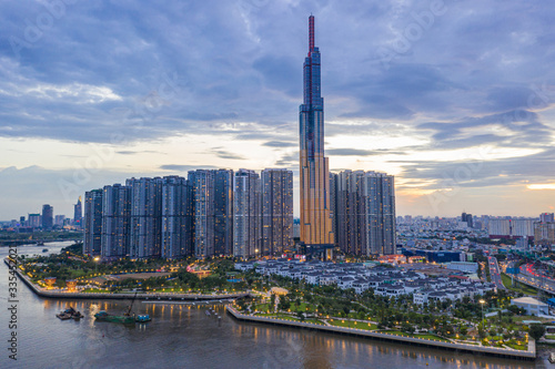 Tall buildings on along riverbank under cloudy sky in evening